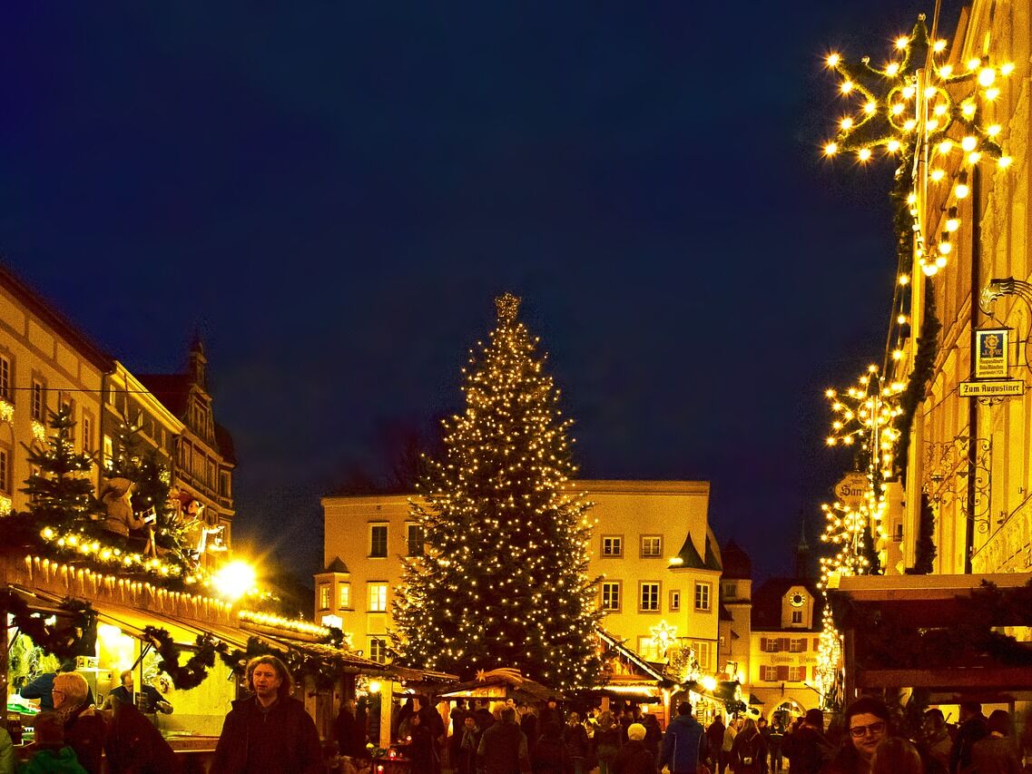 Der rosenheimer Christkindlmarkt mit festlicher Weihnachtsbeleuchtung und einem großen Weihnachtsbaum