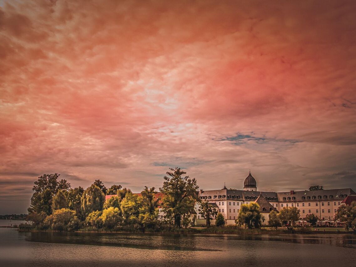 Blick über den Chiemsee auf die Fraueninsel, mit rötlichem Himmel