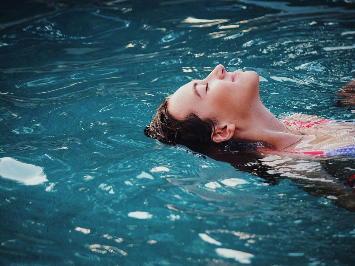 Eine Frau die auf dem Rücken durch das Wasser schwimmt