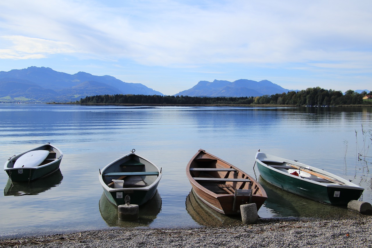 Blick auf den Chiemsee an dem vier kleine Boote am Ufer schwimmen